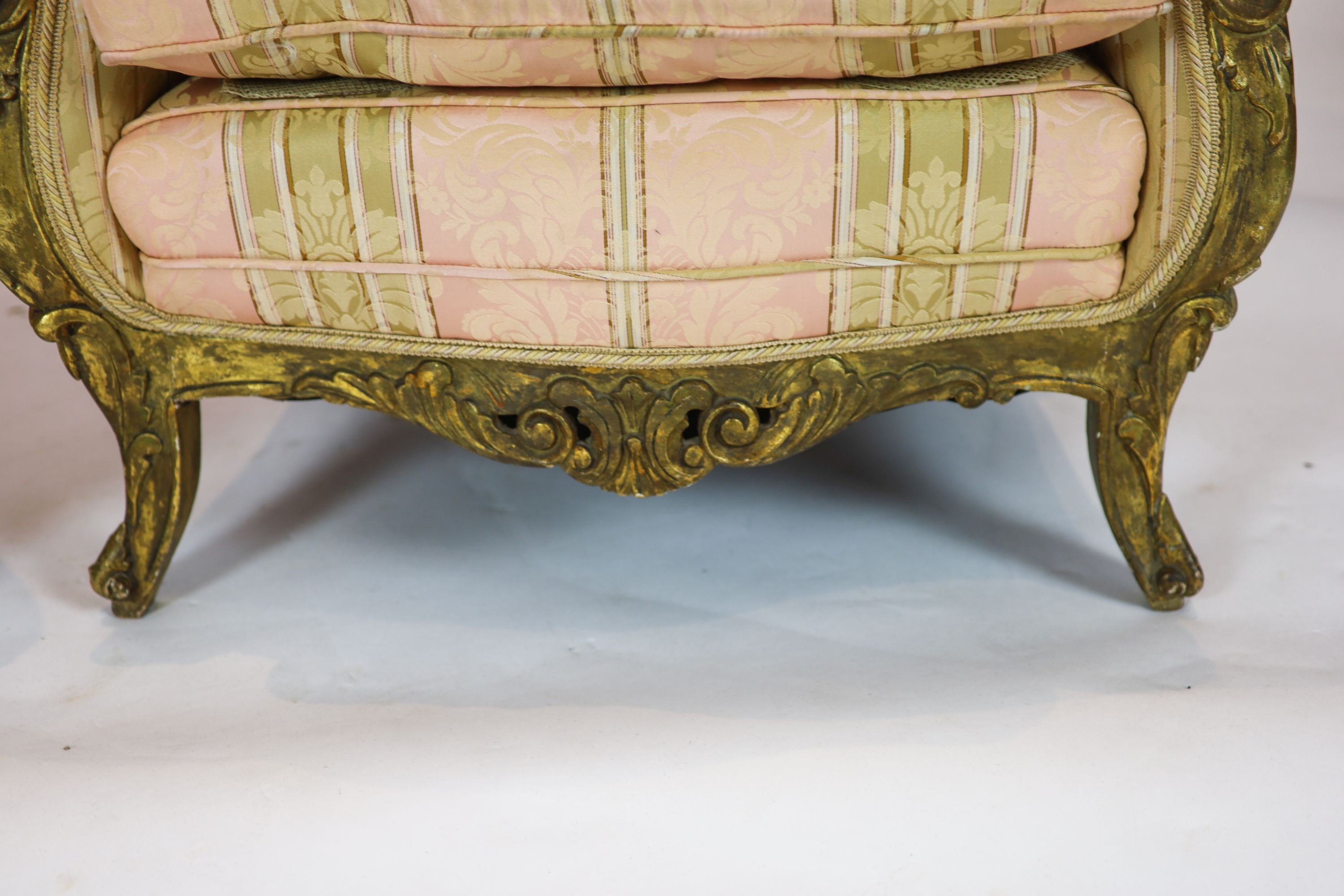 A Louis XV style carved gilt wood five piece suite, consisting of a three seater settee and four fauteuils, all with scroll carved backs and arms, on short cabriole legs